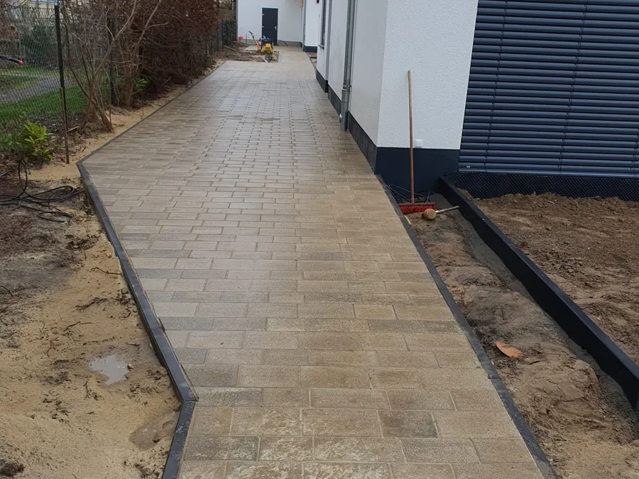 Gepflasterter Gartenweg entlang einer Hauswand mit gerader Kantenführung