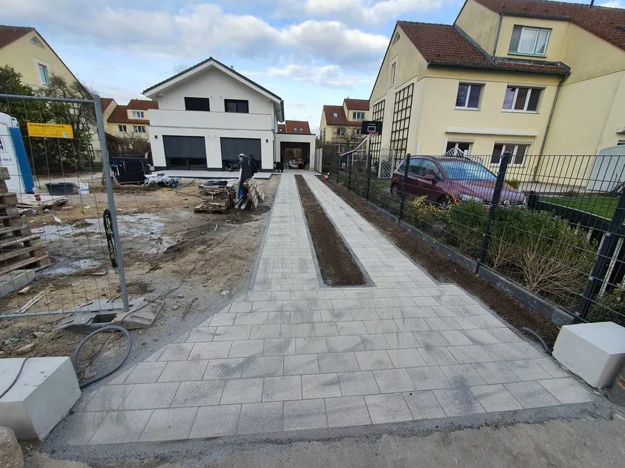 Gesetzte Randsteine und Rinne entlang einer neu gepflasterten Zufahrt