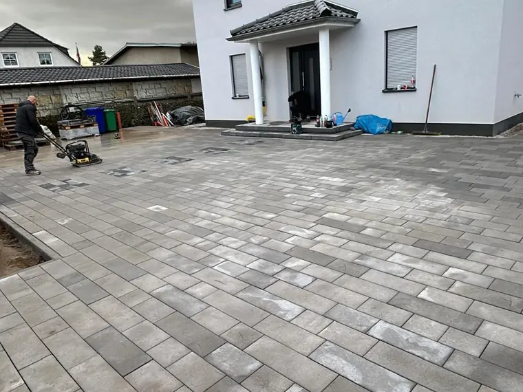 Gepflasterte Einfahrt aus grauen Betonsteinen vor einem Doppelhaus