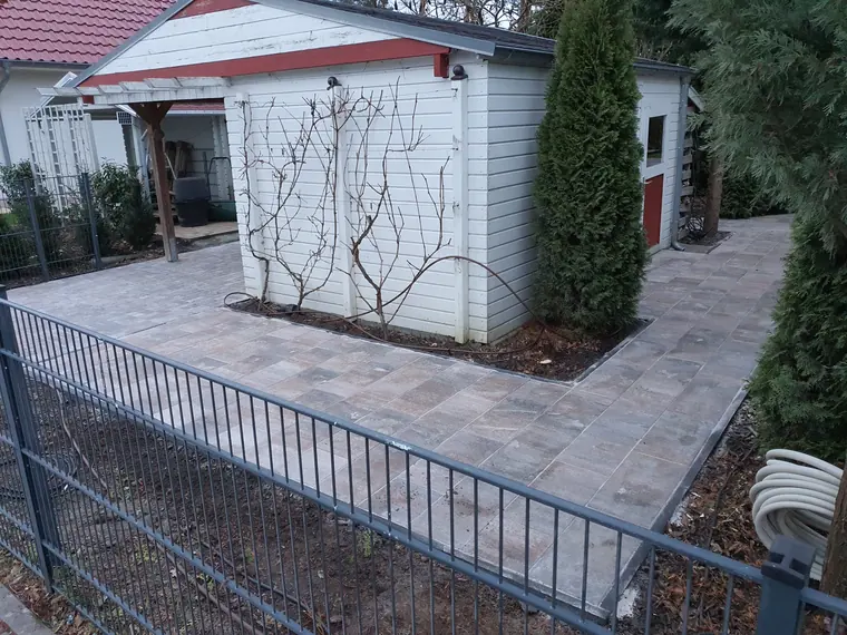 Natursteinterrasse mit Sichtschutzzaun und gerader Kantenführung